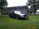 1998 Ford Crown Victoria - A black 1998 Ford Crown Victoria is parked on a grassy lawn in front of a modern building with large windows.
