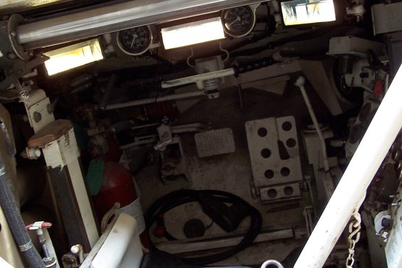 Vehicle interior with gauges, pedals, and a red fire extinguisher