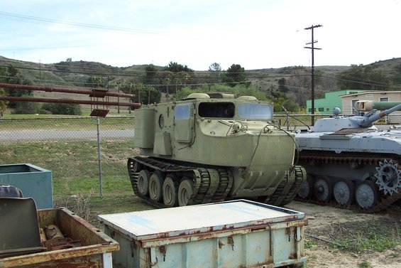 Green tracked vehicle with large windows and a tank to its right