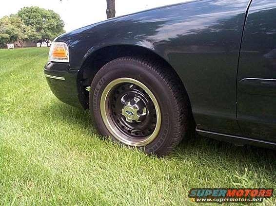Front fender, headlight, and wheel of a dark green sedan parked on grass