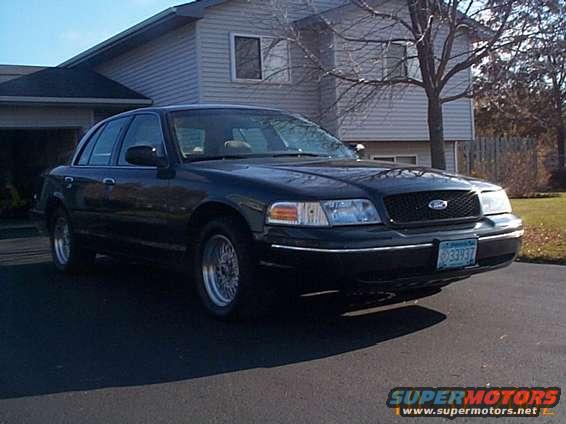Black 1998 Ford Crown Victoria parked in driveway. Front grille has Ford logo. License plate visible