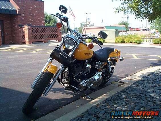 Yellow Harley-Davidson motorcycle parked on asphalt next to a curb
