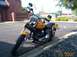 1998 Ford Crown Victoria - A yellow motorcycle is parked on the side of a road with a brick building in the background.