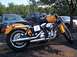 1998 Ford Crown Victoria - A yellow Harley-Davidson motorcycle is parked outdoors next to several cars.