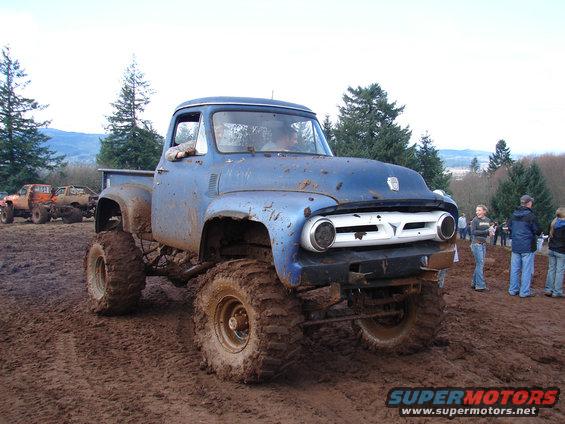 Blue 1956 Ford F-100 pickup truck with large tires in mud