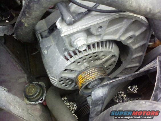 close-up of a vehicle alternator with a pulley and some hoses