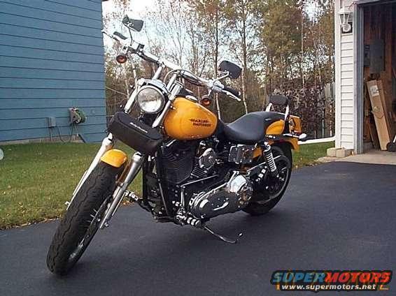 Yellow Harley-Davidson motorcycle parked on asphalt driveway in front of garage
