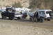 1995 Ford Bronco - A man exits a modified silver Ford Bronco parked on a dirt road with other vehicles and RVs in the background.