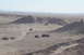 1995 Ford Bronco - Multiple off-road vehicles traverse a desert terrain with sandy hills under a clear sky.