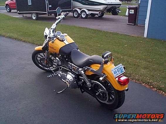 Yellow motorcycle with black seat and chrome accents, parked on asphalt