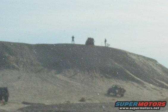 Two off-road vehicles on a sandy incline under a hazy sky