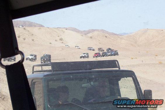 Several off-road vehicles traverse a desert terrain