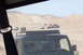 1995 Ford Bronco - A convoy of off-road vehicles navigates through a sandy, arid landscape under a clear sky.