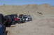 1995 Ford Bronco - Multiple off-road vehicles traverse a desert landscape, kicking up dust on the sandy hills.