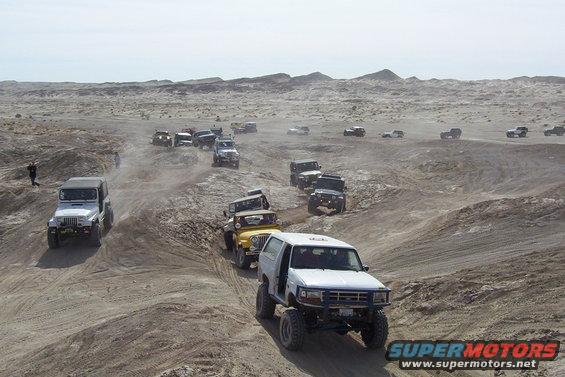 1995 Ford Bronco leading a convoy of off-road vehicles on a dusty trail