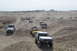 1995 Ford Bronco - A group of off-road vehicles, including a 1995 Ford Bronco, navigate a desert terrain.