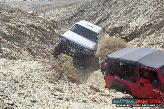 1995 Ford Bronco descending a steep, rocky trail with a red Jeep Wrangler following