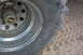 1995 Ford Bronco - A close-up view of a chrome wheel with a WARN locking hub and a large tire, set against a sandy background.