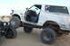 1995 Ford Bronco - Modified 1995 Ford Bronco with oversized tires is shown off-roading next to another vehicle.
