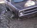 1980 Dodge Magnum - A 1980 Dodge pickup truck is stuck in thick mud, showing its front grille and headlight.