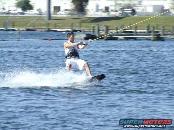 Wakeboarder on water with spray, Supermotors logo at bottom right