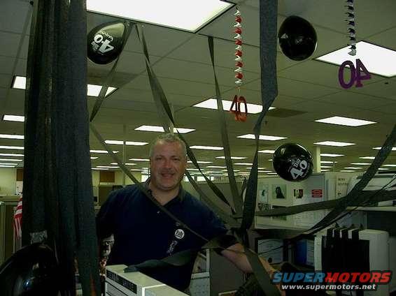 man in office with balloons and streamers, some say 40