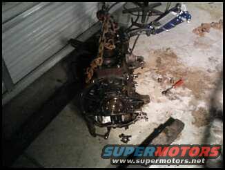 Engine assembly hanging from a chain hoist in a garage