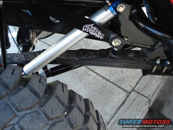 Close-up of off-road suspension with 'Archie's OVERKILL' shock absorber and large tire tread