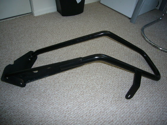 Black metal part with two curved bars and mounting brackets, on carpet
