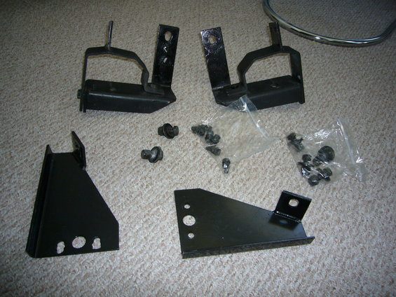 Four black metal brackets and assorted screws and bolts on a carpeted surface