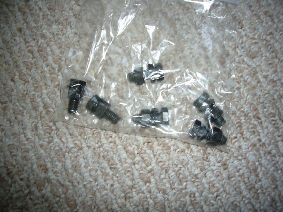 Bag of metal bolts with hex heads, lying on a carpeted surface