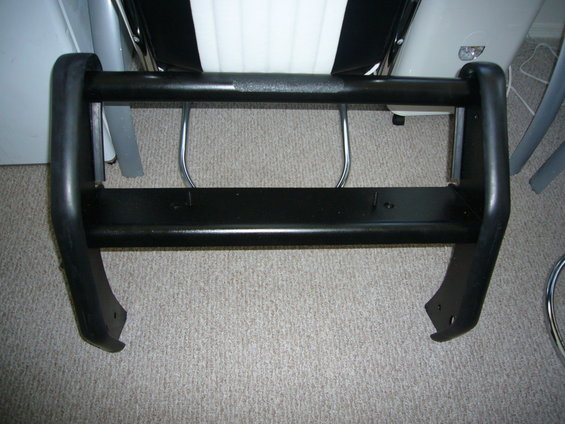 Black bull bar with two horizontal bars and curved uprights, resting on carpet