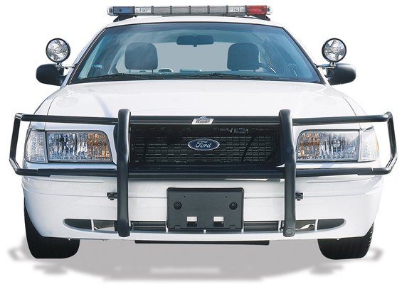 White Ford police sedan with black grille guard, A-pillar lights, and roof light bar, front view.