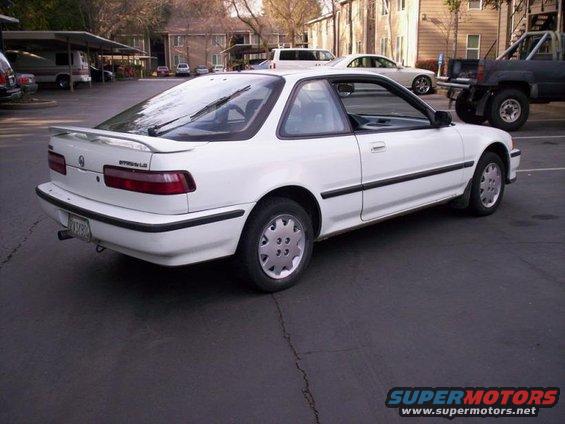 White coupe with a rear spoiler, parked in a lot