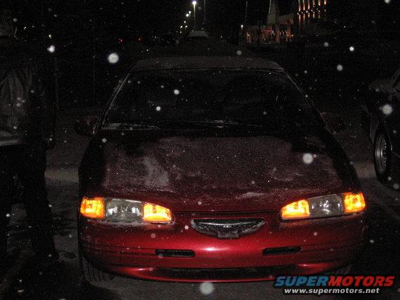 red car front view at night, snow falling