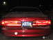 1995 Ford Thunderbird - The rear of a red sedan, possibly a 1995 Ford Thunderbird, is shown at night with snow falling.