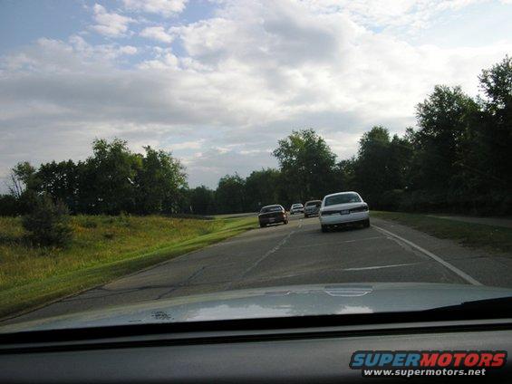 White 1988 Mercury Grand Marquis driving on a highway, rear view