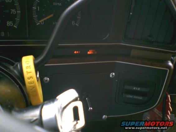 Dashboard with gauges, a yellow wristband on the steering wheel, and 4x4 and low range indicators
