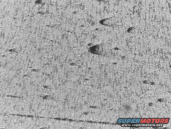 Microscopic view of metal grain structure with dark inclusions