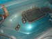 1996 Ford Bronco - A metal patch is welded into the teal-colored floor of a vehicle, with several bolts visible nearby.