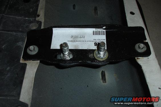 Close-up of a black metal bracket with two bolts, a white label, and a barcode. Label reads 'E-SERIES HD PICKUP 92-96 FRONT BUMPER BRACKET KIT'