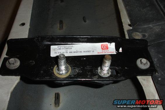 Black metal mounting bracket with two bolts and a label reading "FD P/U 92-95 ARM MOUNTING BRACKET LH"
