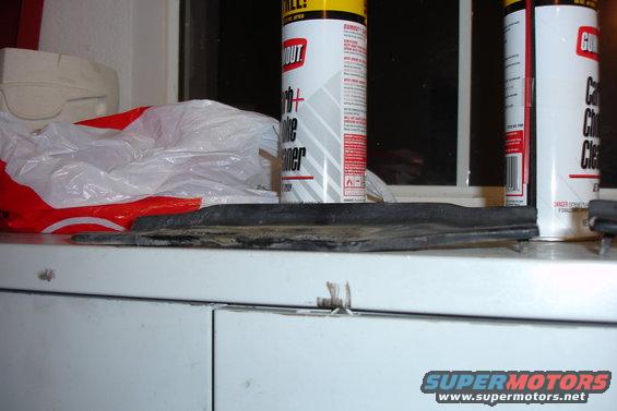 rubber trim piece and two cans of cleaner on shelf