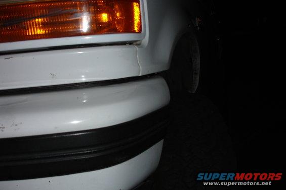 Close-up of white front bumper and amber turn signal on a vehicle