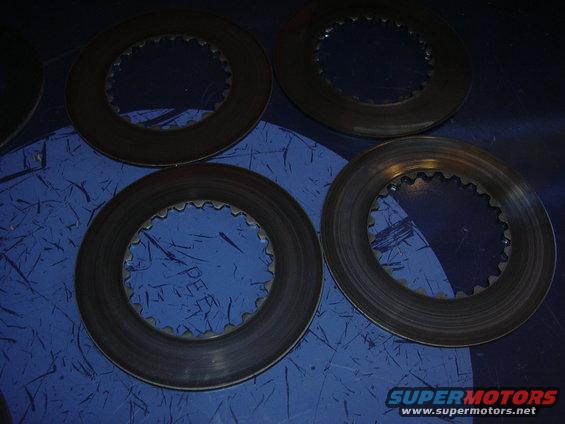Four differential clutch packs with toothed inner edges on a blue surface