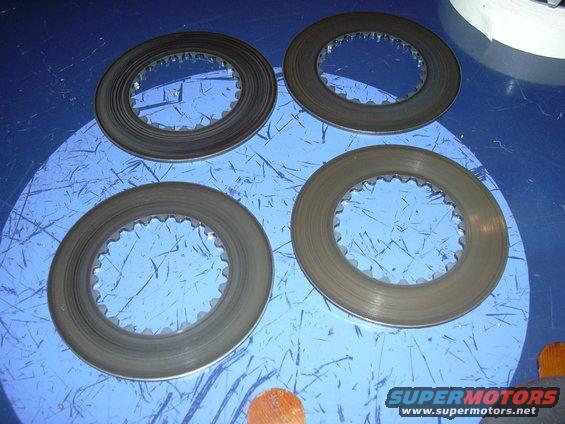 Four clutch discs with toothed inner edges on a blue surface