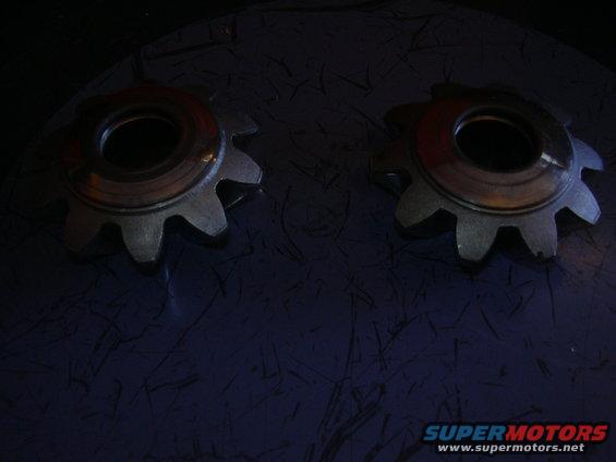 Two metal gears with ten teeth each, resting on a dark textured surface