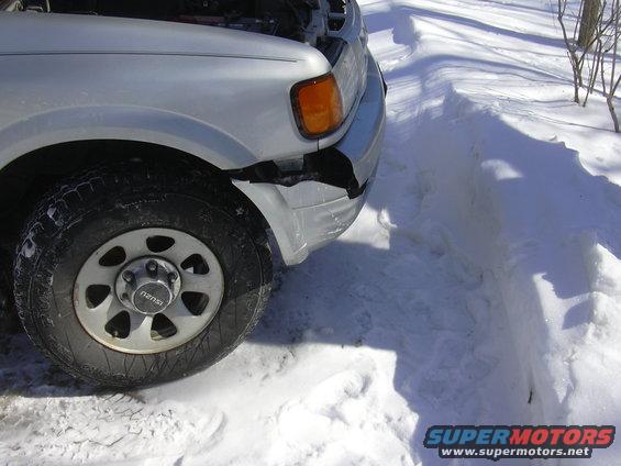 Silver SUV's front bumper is cracked and damaged, parked in snow with hood open
