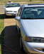 1995 Ford Thunderbird - A silver 1995 Ford Thunderbird is parked in front of a white one, showing the front quarter of the silver car.