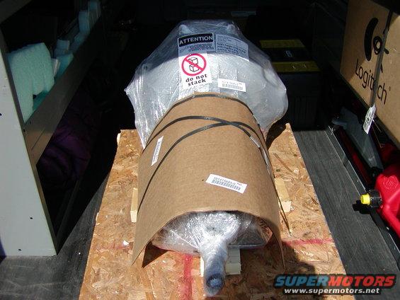 Transmission wrapped in plastic and cardboard, secured with black straps on a wooden pallet